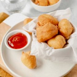 Golden fried chicken nuggets served with a side of ketchup on a white plate. Perfect for snacks, parties, or casual meals.