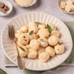 Creamy potato gnocchi with fresh sage on a rustic plate, ready to serve. Perfect comfort food recipe from Baked Bree.