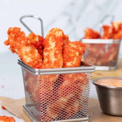 Crispy fried fish fillets in a small metal basket.