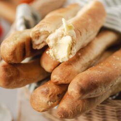 Soft baked baguettes with melting butter on a wicker basket, perfect for bread lovers, easy to make at home.
