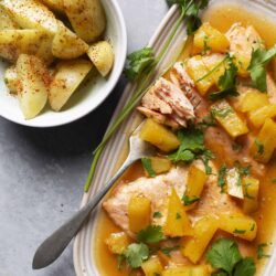 Juicy baked salmon with pineapple and cilantro in a flavorful sauce, served with seasoned potato wedges.