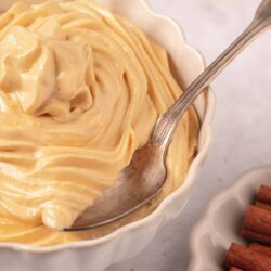 Creamy homemade vanilla pudding in a white scalloped bowl with a spoon.