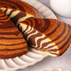 Fluffy zebra cake with chocolate and vanilla layers on white serving platter.