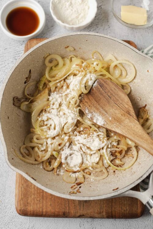 Creamy sautéed onions and mushrooms cooking in a skillet with flour, butter, and seasonings.