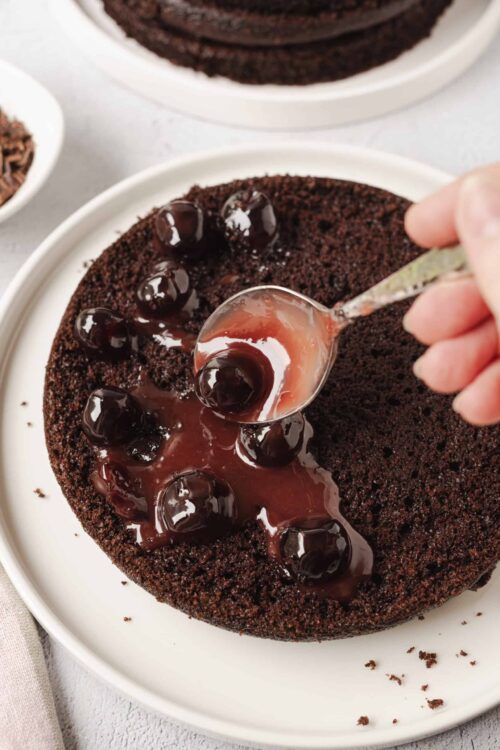Rich chocolate cake with cherry filling and glossy cherries on top, perfect for dessert lovers.
