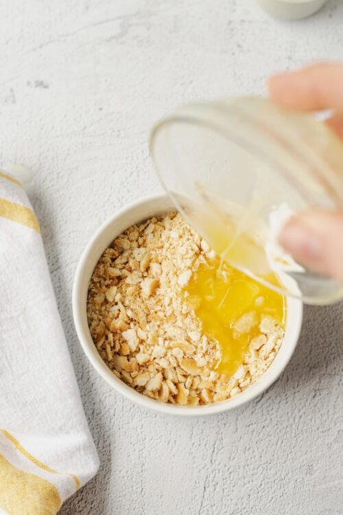 Crushed cookies and melted butter for pie crust preparation.
