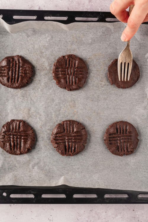Rich chocolate cookies with fork marks on a baking sheet, freshly baked and ready to enjoy.