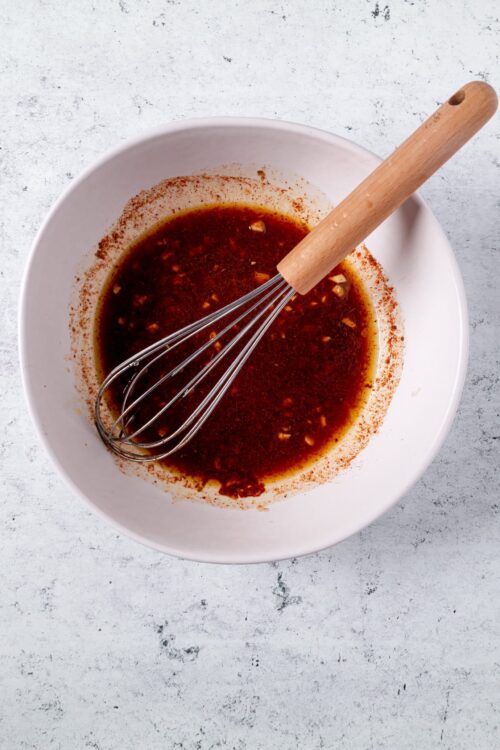 Savory homemade barbecue sauce with garlic in a white mixing bowl.