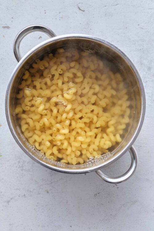 Cooked macaroni pasta in a stainless steel pot, ready for baking or cooking.