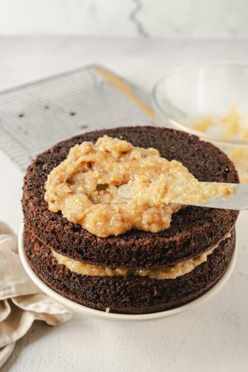 Chocolate cake with caramel filling being spread between layers.