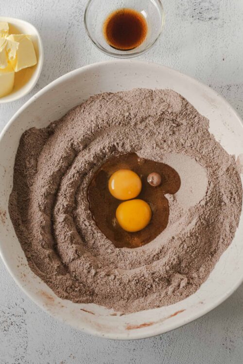 Flour, eggs, and ingredients for chocolate cake batter preparation.