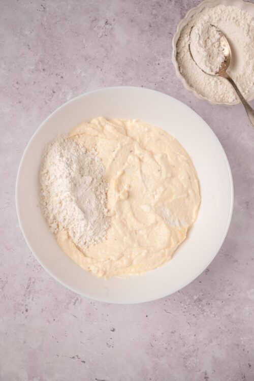 Flour and batter mixture in white bowl for baking bread or cake.
