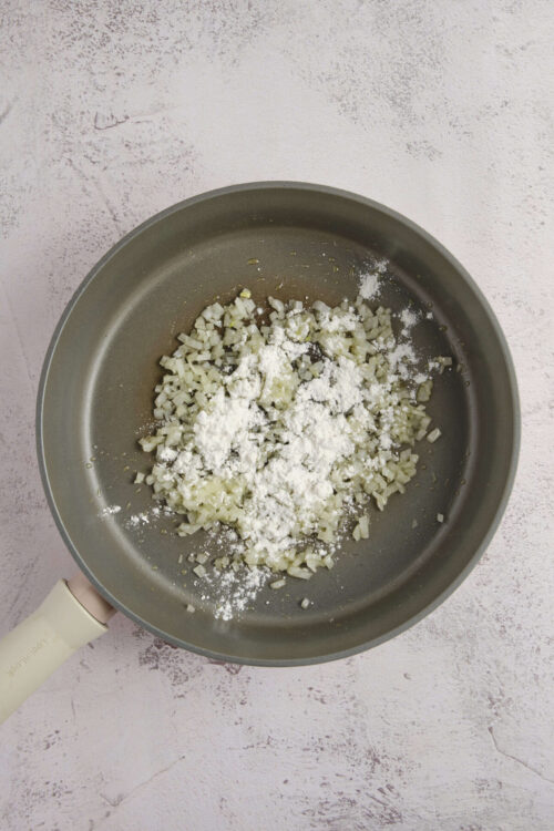 Sautéed onions with salt and flour in a frying pan for baking recipes.