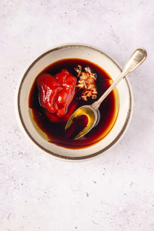 Savory homemade barbecue sauce with ketchup, soy sauce, and garlic on white textured background.