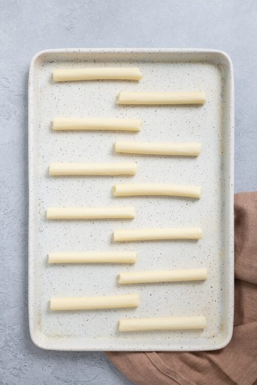 Thin white chocolate sticks on a speckled baking sheet for baking recipes.
