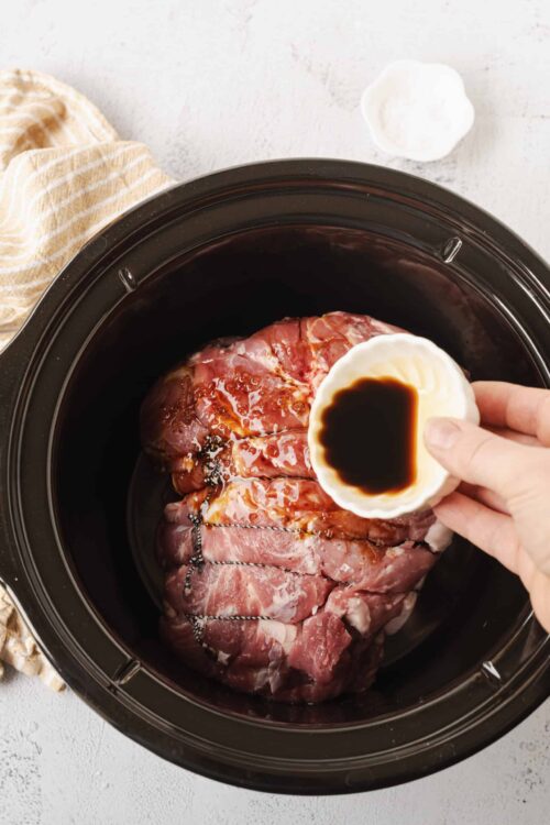 Juicy marinated pork roast in slow cooker with soy sauce and seasoning.