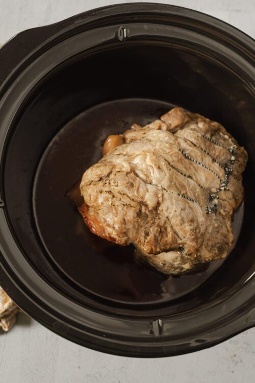 Juicy pot roast cooking in slow cooker with seasoned beef and vegetables.