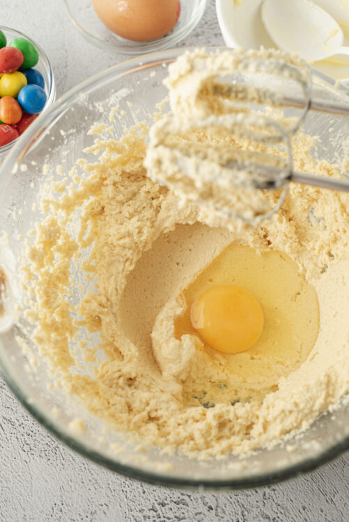 Fluffy cookie dough mixture with egg in a glass bowl, ready for baking.