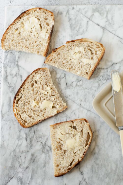 Fluffy butter bread slices with melting butter on marble surface, homemade bread baking.