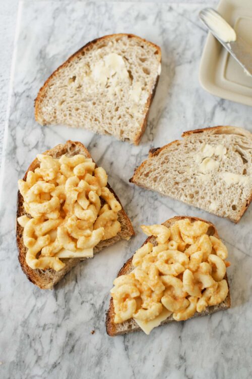 Creamy macaroni and cheese grilled cheese sandwiches on sourdough bread with butter.