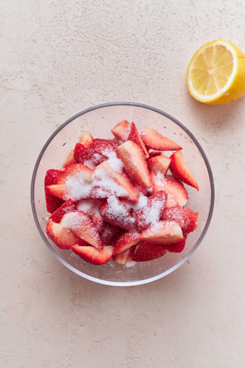 Fresh strawberry slices with sugar in a glass bowl for strawberry dessert or baking.