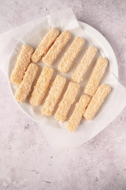 Coconut-covered fish sticks on a white plate.
