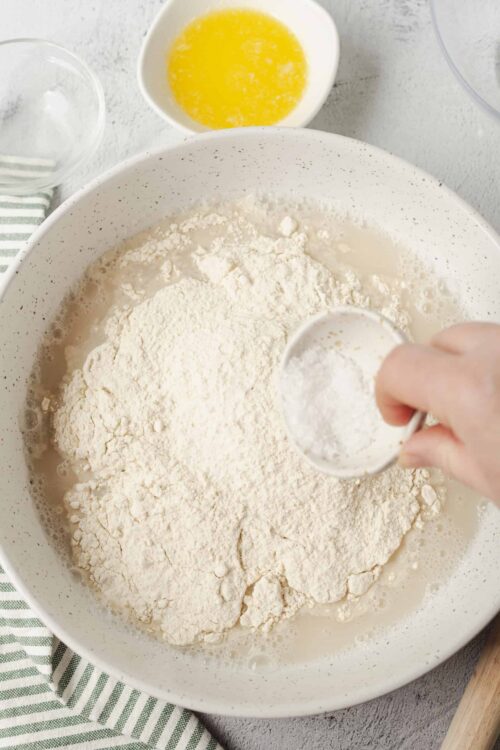 Flour being added to a mixing bowl for baking.
