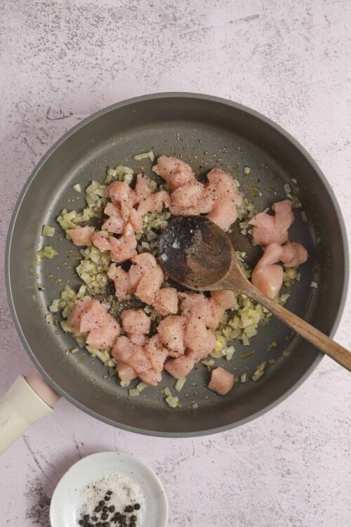 Sauteing diced chicken and chopped onions in a non-stick skillet for flavorful chicken recipes.