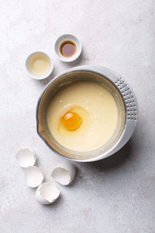 Creamy batter with a raw egg in a mixing bowl, ready for baking or cooking.