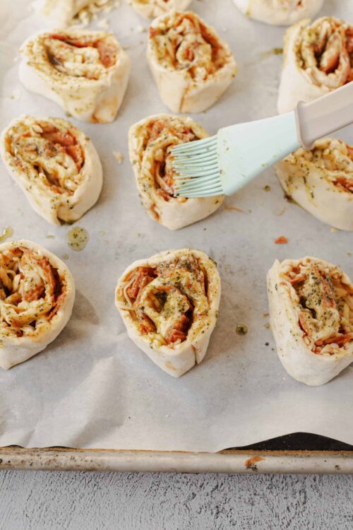 Cream cheese pinwheels with ham, cheese, and herbs on parchment paper.