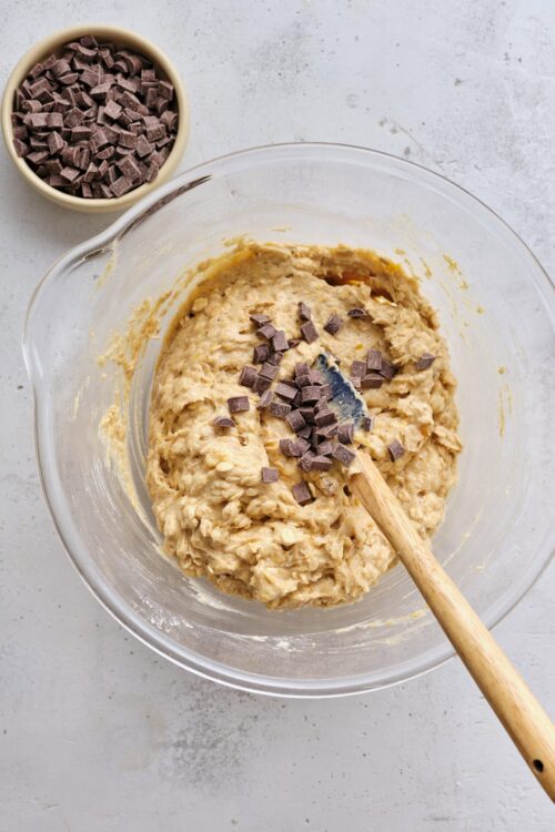 Rich chocolate chip cookie dough in a glass mixing bowl.