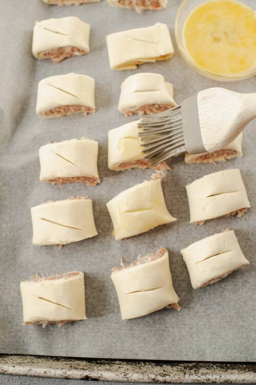 Cream cheese-stuffed pastry bites being assembled on parchment paper.