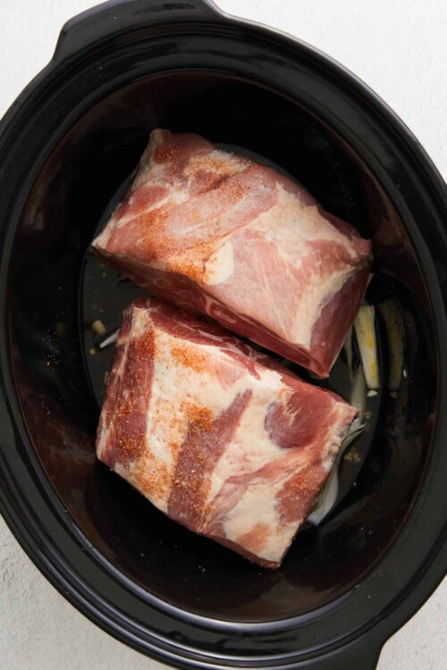 Seasoned beef chuck roast in a slow cooker ready for cooking, ideal for tender pot roast recipes.