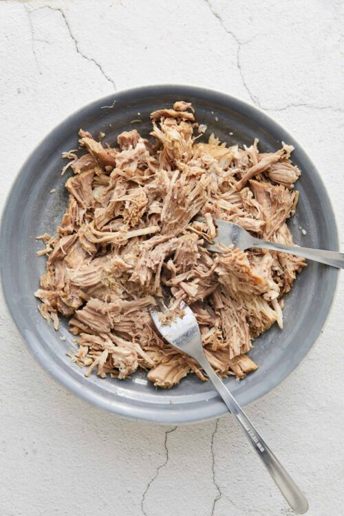 Shredded cooked chicken on gray plate for recipes or meal prep.