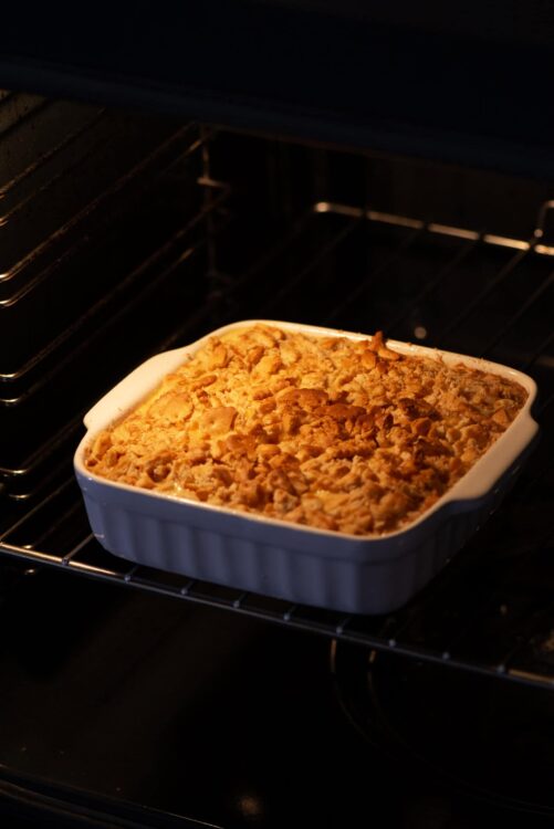 Golden baked apple crumble in baking dish inside oven.