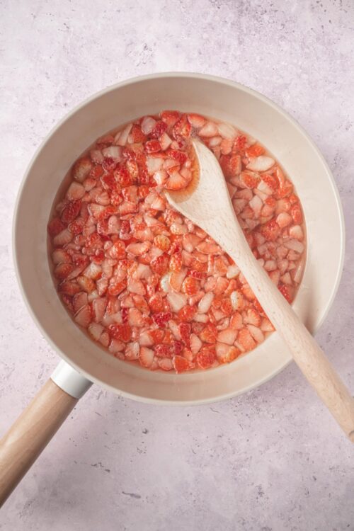 Fresh strawberry compote in a white pot with a wooden spoon. Perfect for breakfast or desserts.