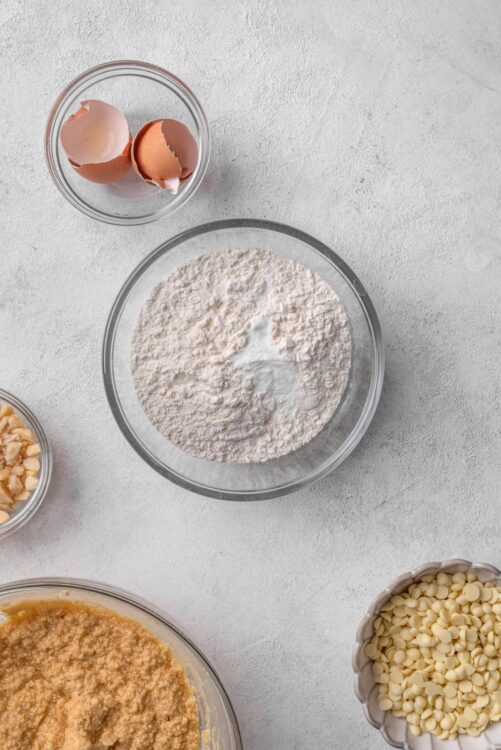 Cracked eggs and baking ingredients in glass bowls for cookie or cake baking.