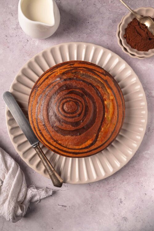 Freshly baked banana bread with a cinnamon swirl on a white scalloped plate.