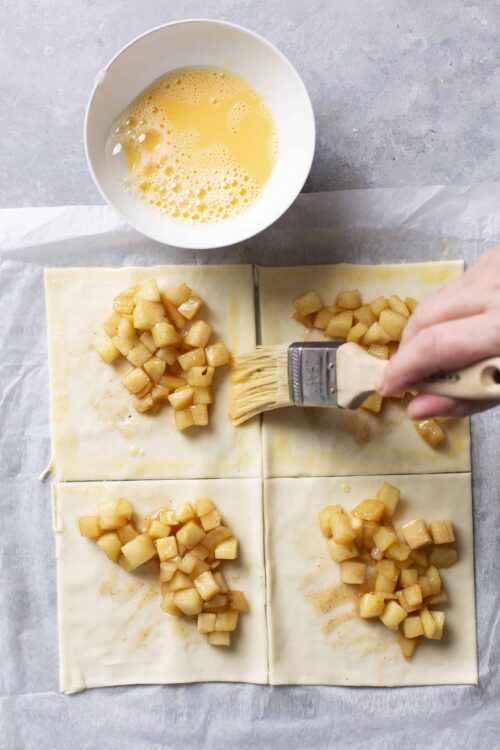 Sweet apple filling being spread on puff pastry for delicious homemade pastries.
