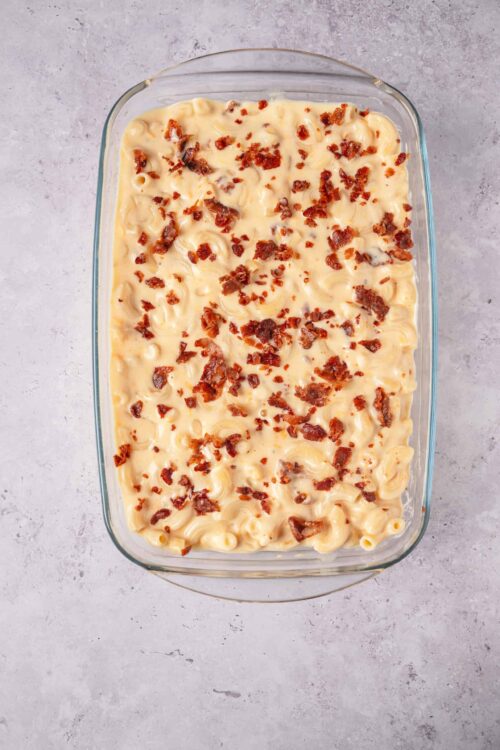 Creamy macaroni and cheese bake topped with crispy bacon bits, served in a glass baking dish.