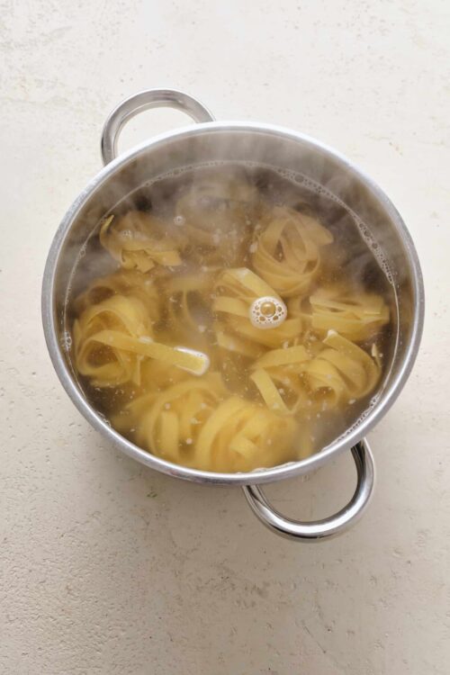 Pasta boiling in a stainless steel pot on a kitchen counter.