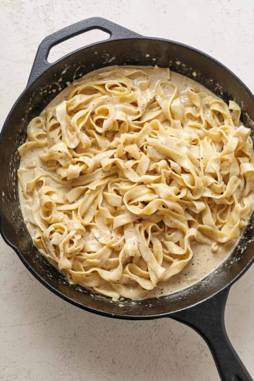 Creamy homemade fettuccine Alfredo in a cast iron skillet. Perfect comfort food with rich, cheesy sauce.