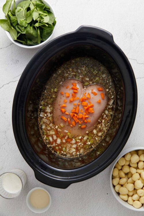 Succulent chicken breast in slow cooker with vegetables and herbs, perfect for savory dinner recipes.