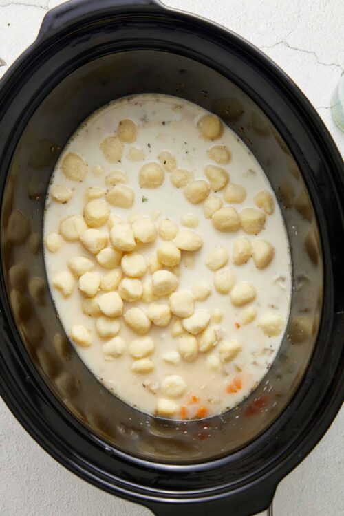 Creamy gnocchi cooking in a slow cooker with sauce.