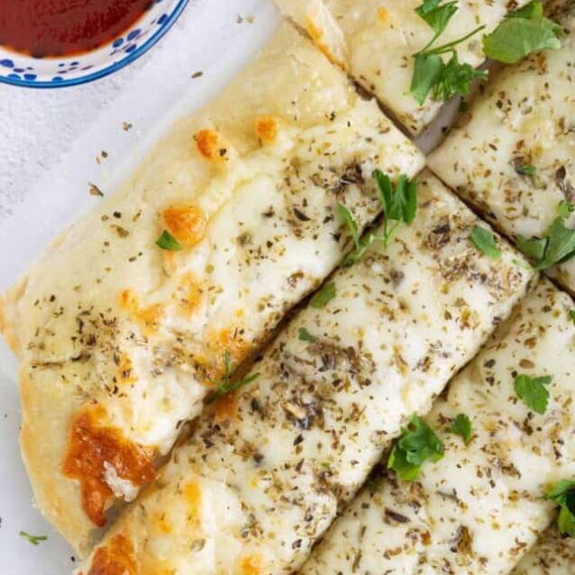 Cheese and herb stuffed garlic bread sticks served with marinara sauce, topped with fresh herbs.
