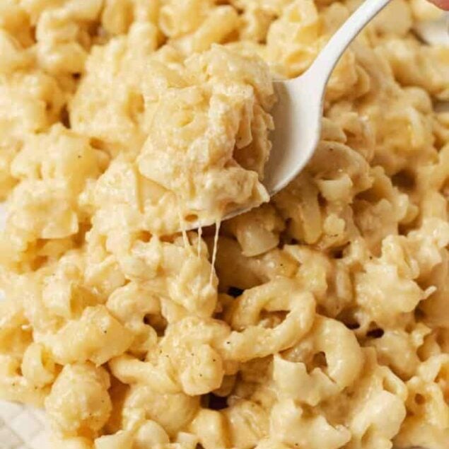 Buttery mac and cheese in a white bowl with a spoon.
