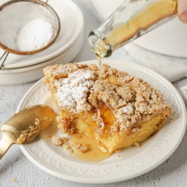 Butter being poured over crumb-topped casserole on a white plate.
