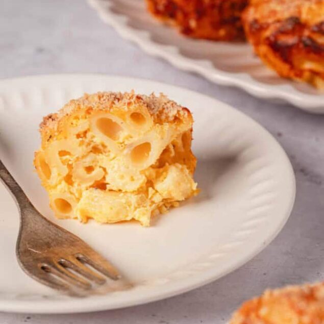 Creamy baked mac and cheese with a golden breadcrumb topping on a white plate.