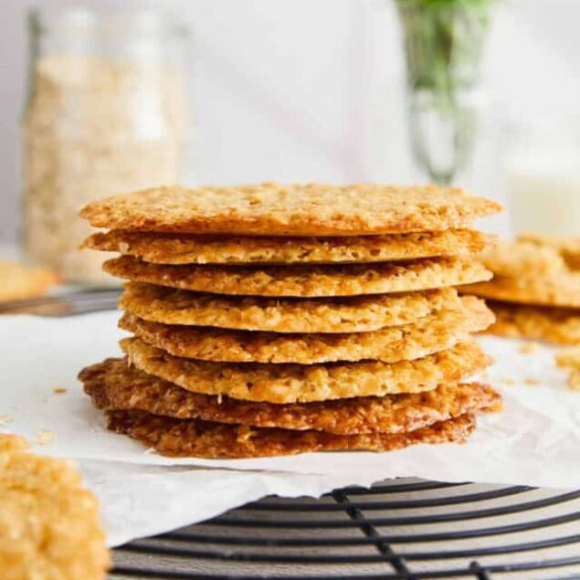 Golden crispy oatmeal cookies stacked on parchment paper, perfect for baking and snacking.