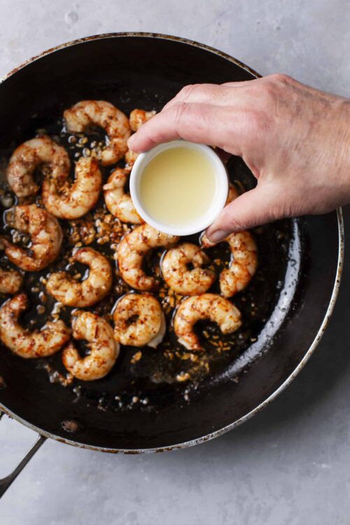 Juicy shrimp being cooked in a skillet with garlic and spices.